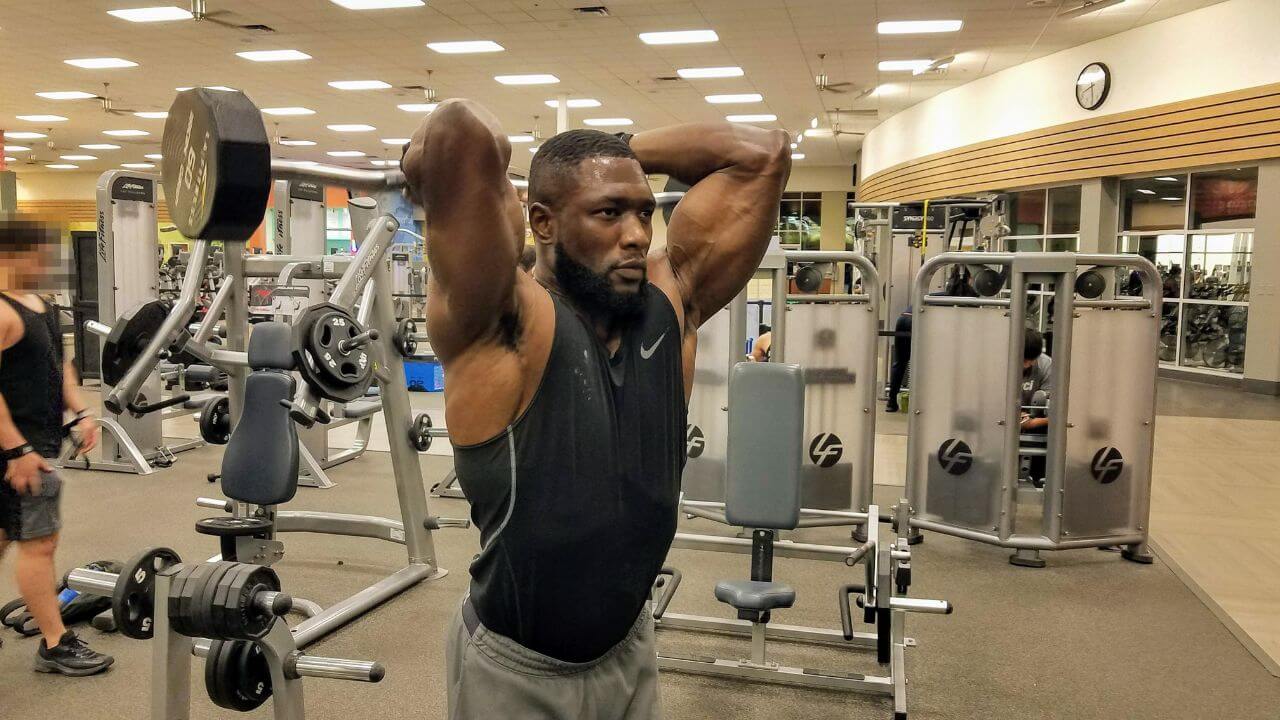 Nurudeen performs overhead barbell triceps extension