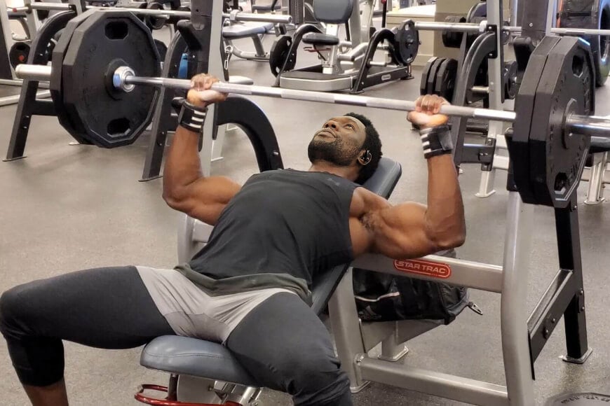 Nurudeen performs an incline bench press during a workout